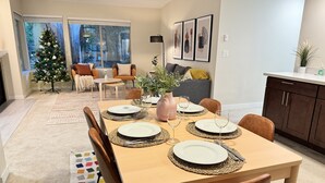 Een eetruimte met een tafel voor vier personen, een kerstboom en uitzicht op het buiten.