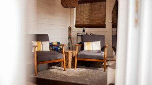 Une pièce chaleureuse avec deux chaises en bois, une petite table en bois et un luminaire suspendu en fibres tressées.
