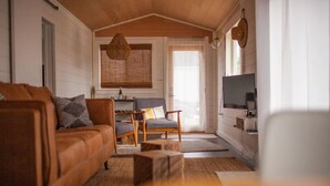 Un salon chaleureux avec un canapé en cuir marron, une table basse en bois, un canapé gris et un téléviseur fixé au mur.