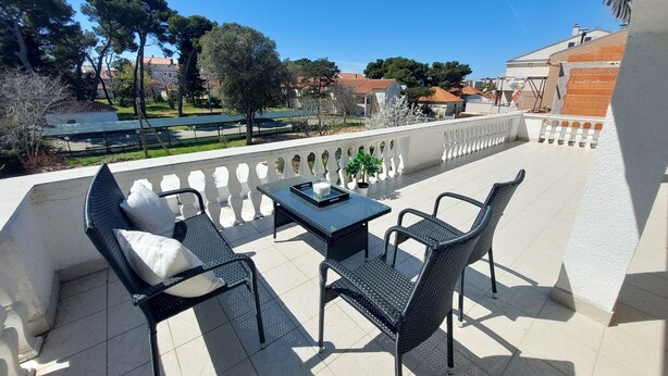 A balcony with a sofa, two chairs, and a table.