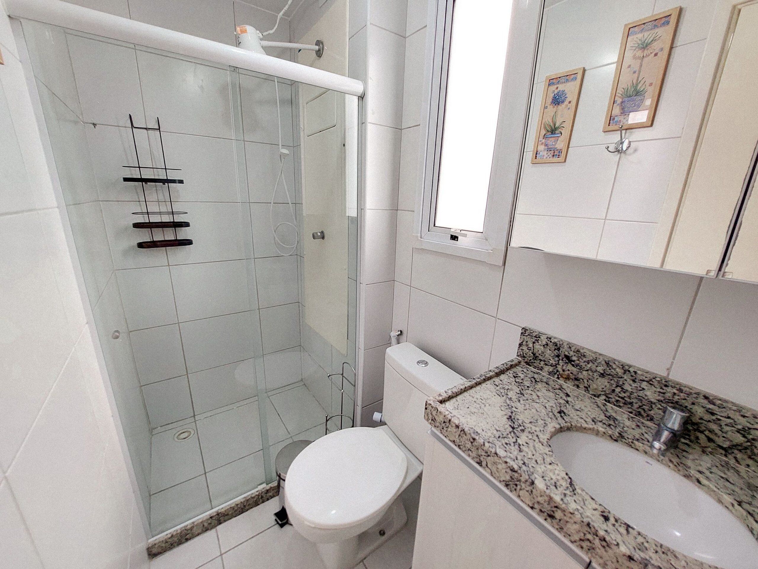Un baño con ducha de vidrio, inodoro y lavamanos de encimera de granito.