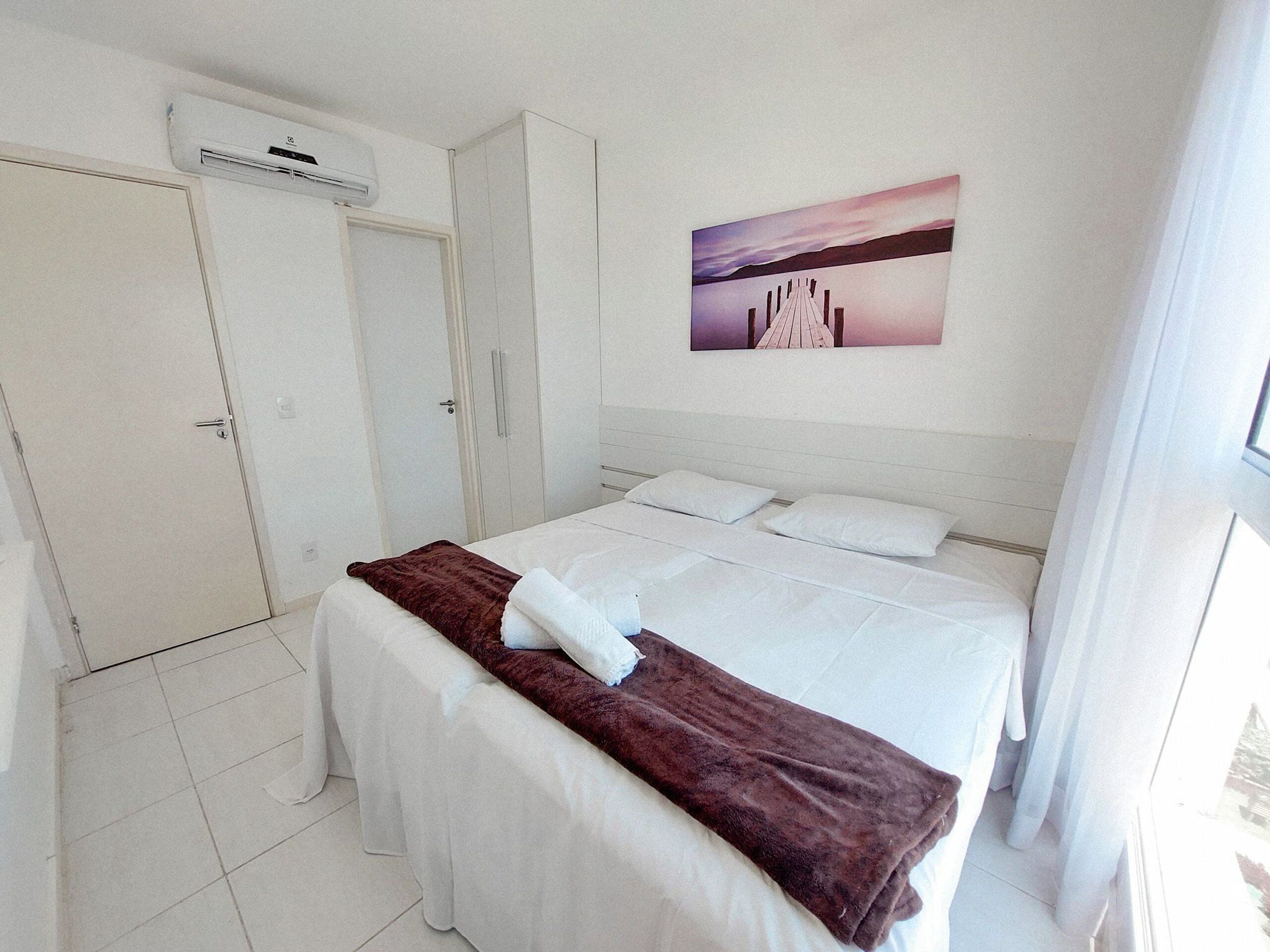 Ein Hotelzimmer mit Bett, Kleiderschrank und einem Bild an der Wand.