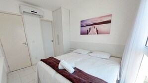 A hotel room with a bed, a wardrobe, and a painting on the wall. - Flats no Muro Alto Clube (Ipojuca)