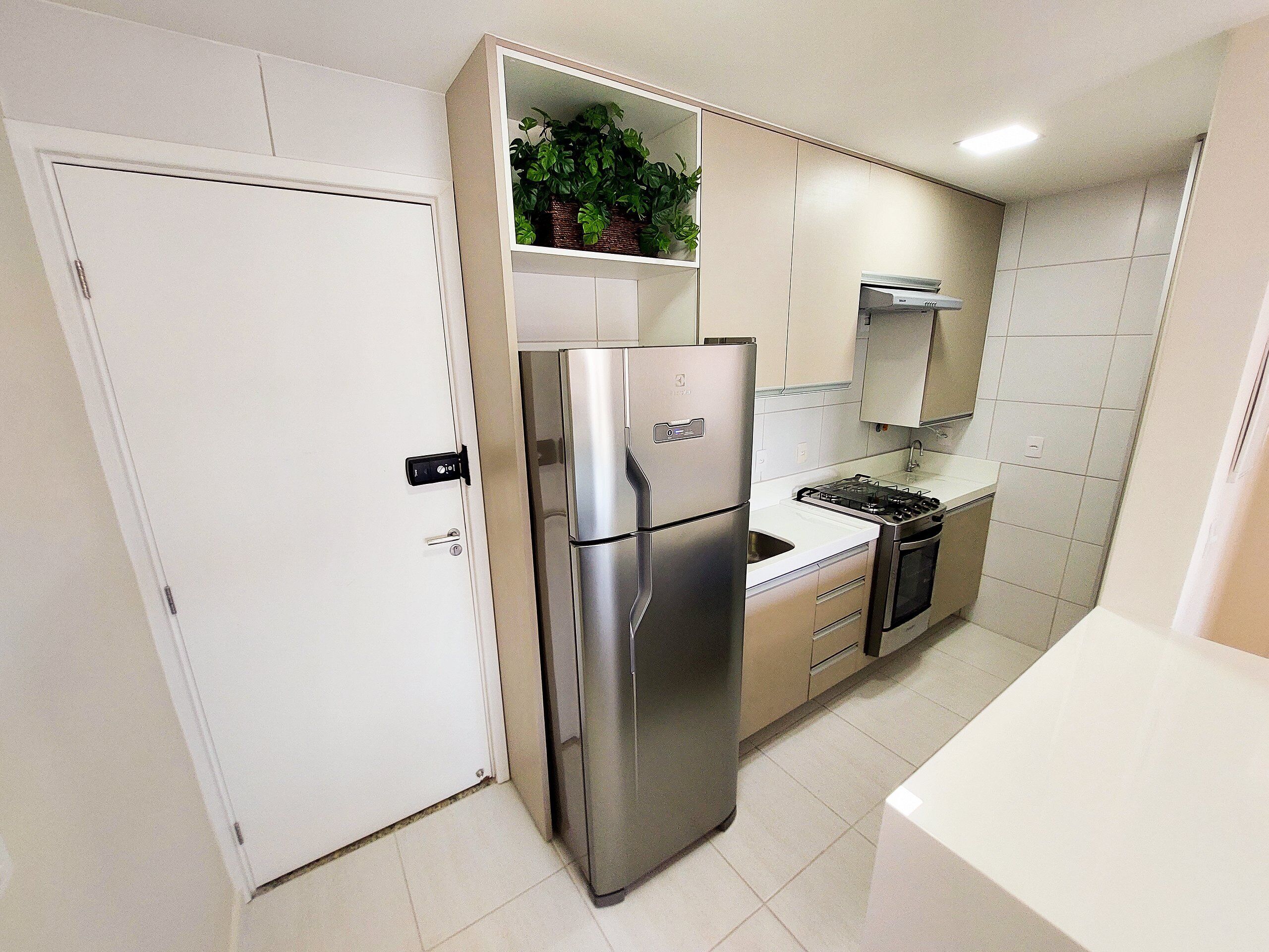 A compact kitchen with a stainless steel refrigerator, a built-in oven, and a gas stove.