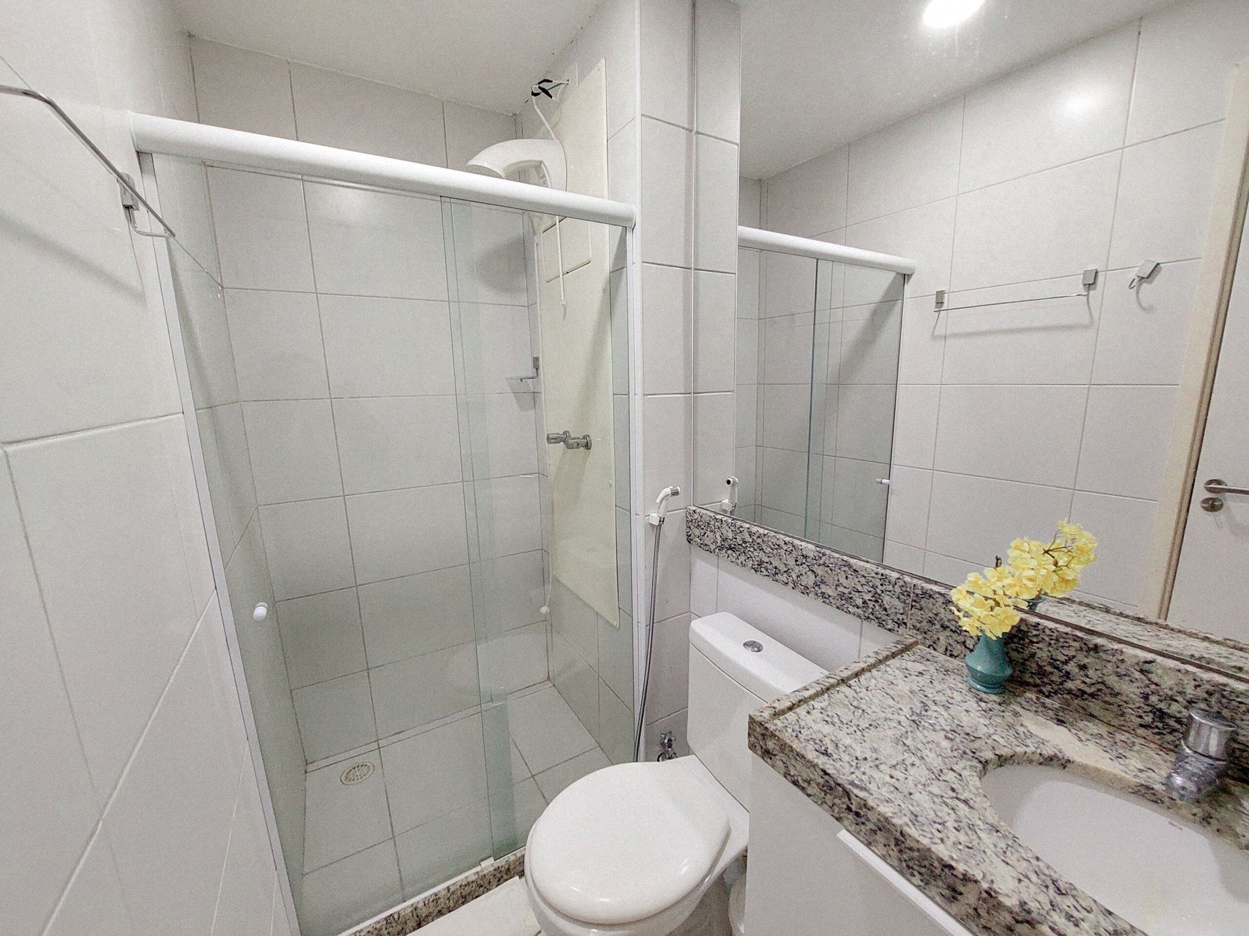 Une salle de bain moderne avec une douche à parois de verre, des toilettes, un lavabo avec un plan de travail en granit et un miroir.
