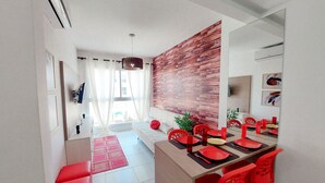 A modern dining area with a wooden accent wall, red chairs, and a long table set for six. - Flats no Muro Alto Clube (Ipojuca)