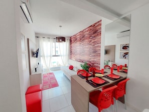 Un comedor moderno con una pared decorada en madera, sillas rojas y una mesa larga dispuesta para seis personas.