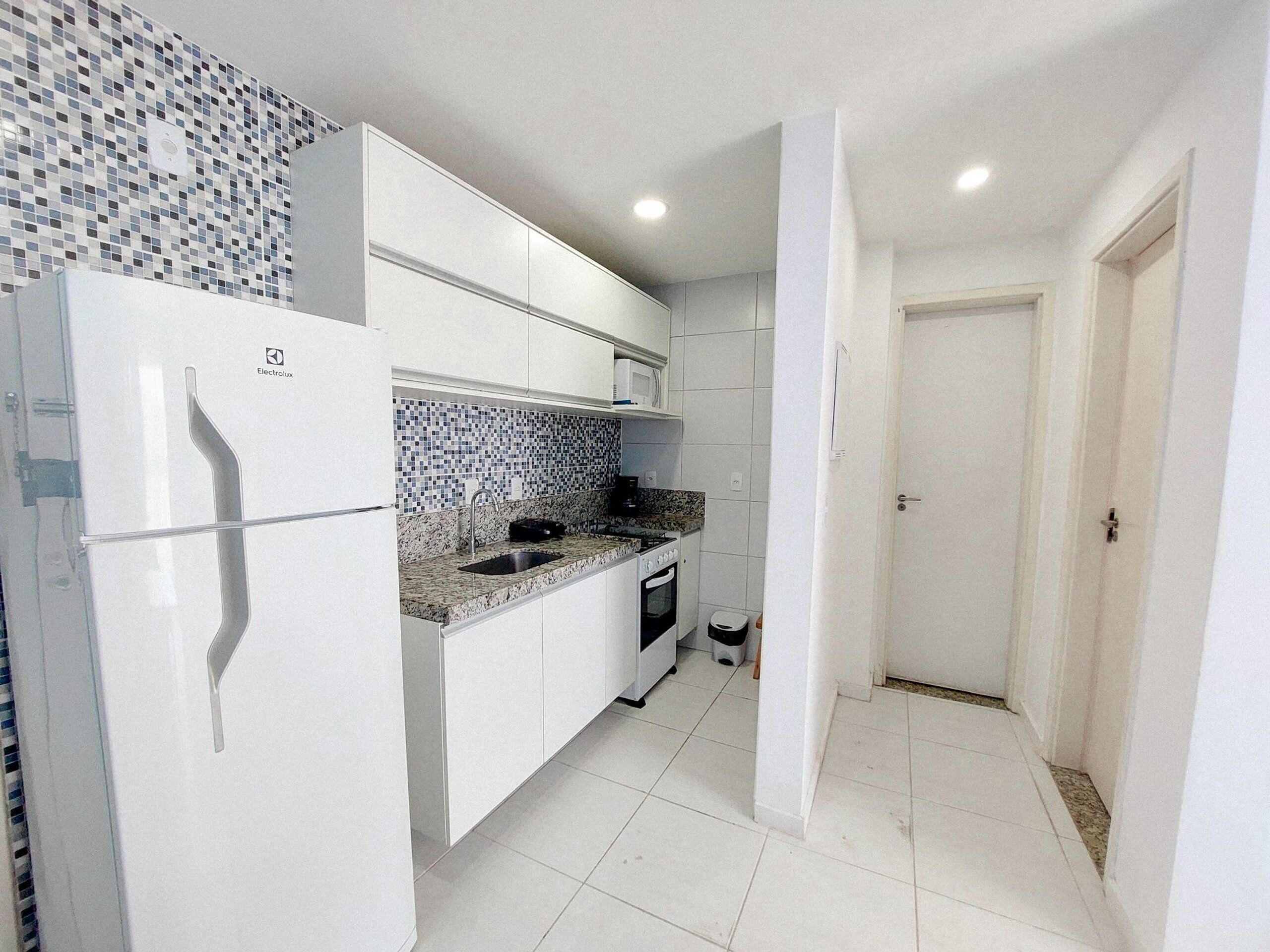 A compact kitchen with white cabinetry, a built-in oven, and a tiled backsplash.