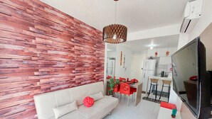 A modern living room with a sofa, dining table, and TV. - Flats no Muro Alto Clube (Ipojuca)