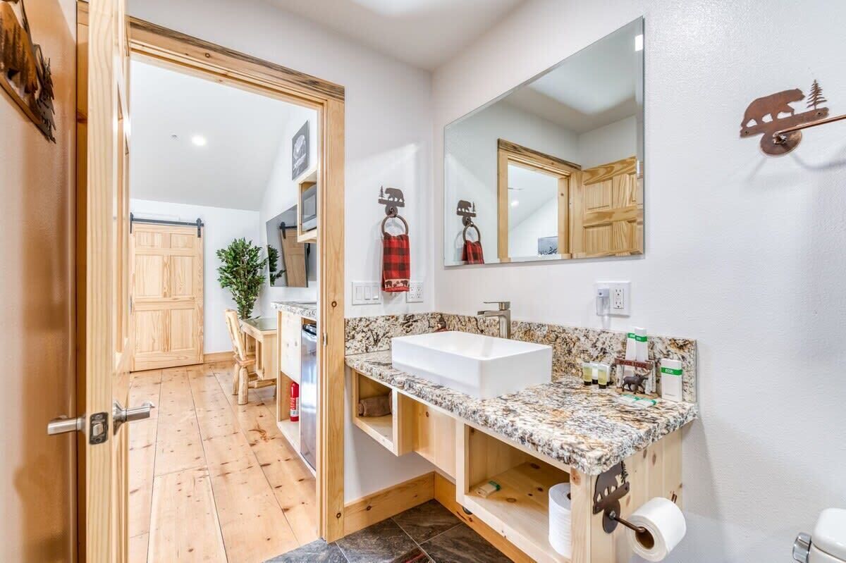 A modern bathroom with a wooden vanity, a large mirror, and a built-in sink.