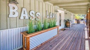 A wooden deck with a sign reading "BASS LAKE" and a planter with tall grasses. - Cottage Like Suite w/ Private Hot Tub (Bass Lake)