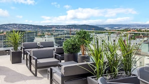 A rooftop terrace with outdoor seating, potted plants, and a city view. - Radisson RED Oslo Økern (Oslo)
