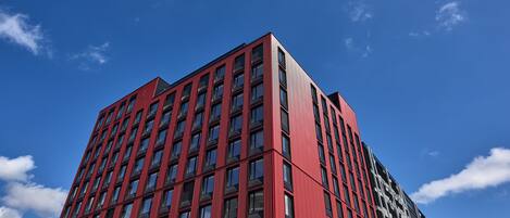 A modern high-rise building with a red facade and multiple windows.