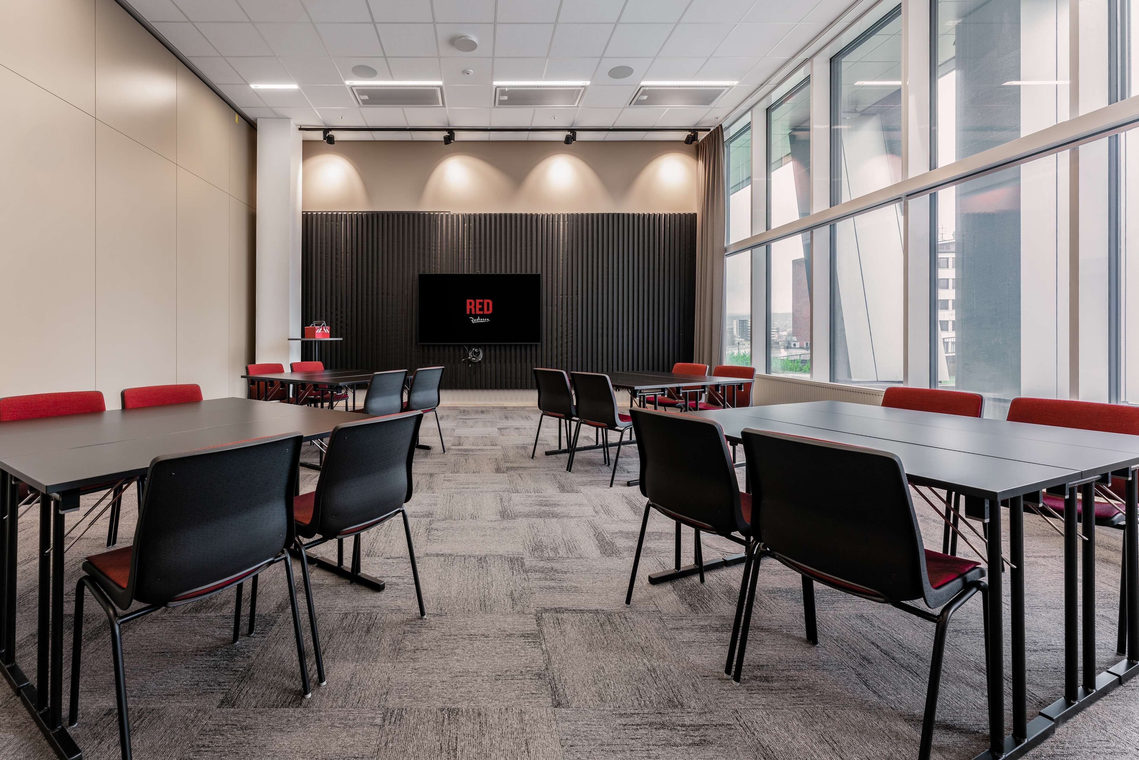 A conference room with a large screen, multiple tables, and chairs.