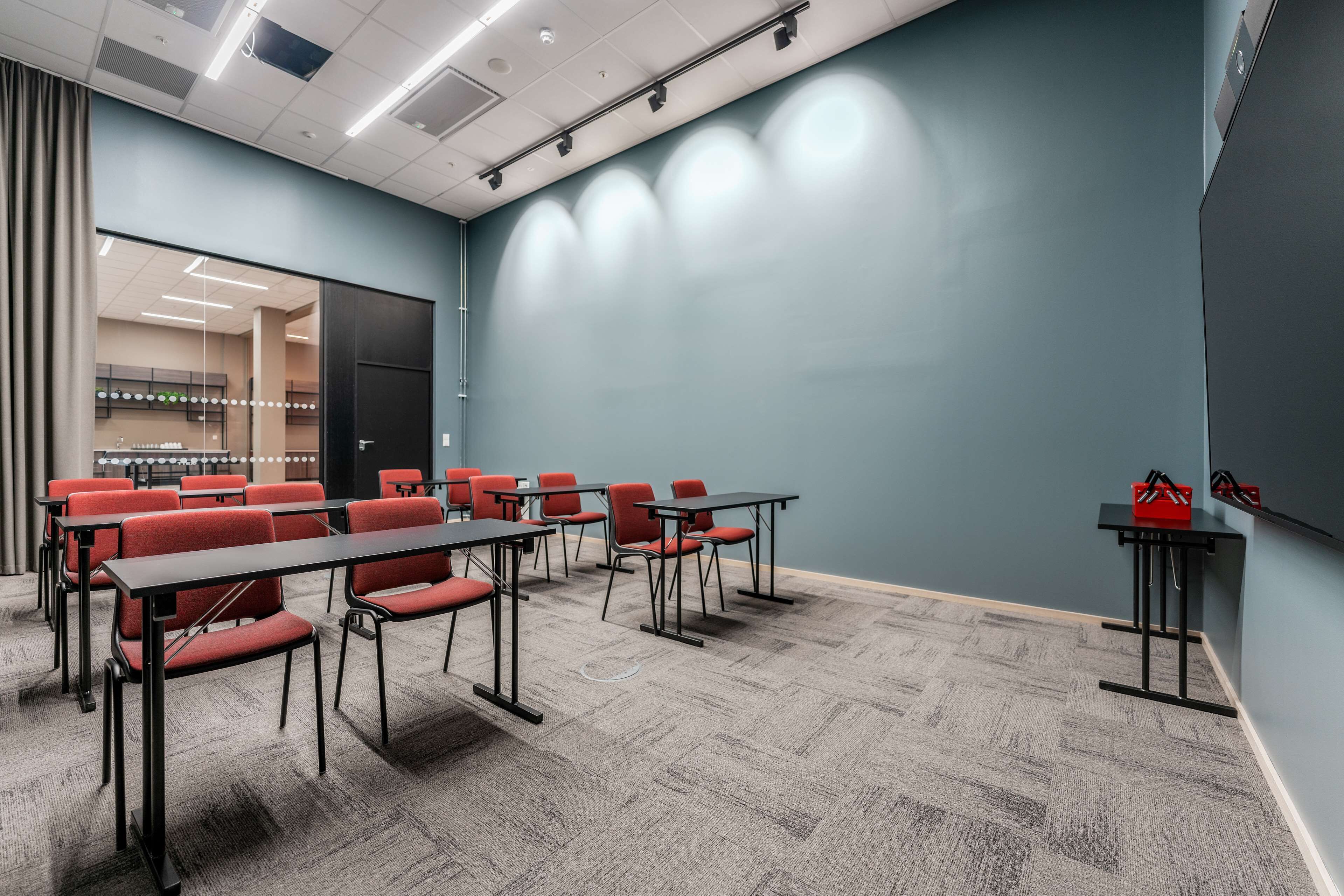 A conference room with a long table, red chairs, and a carpeted floor.