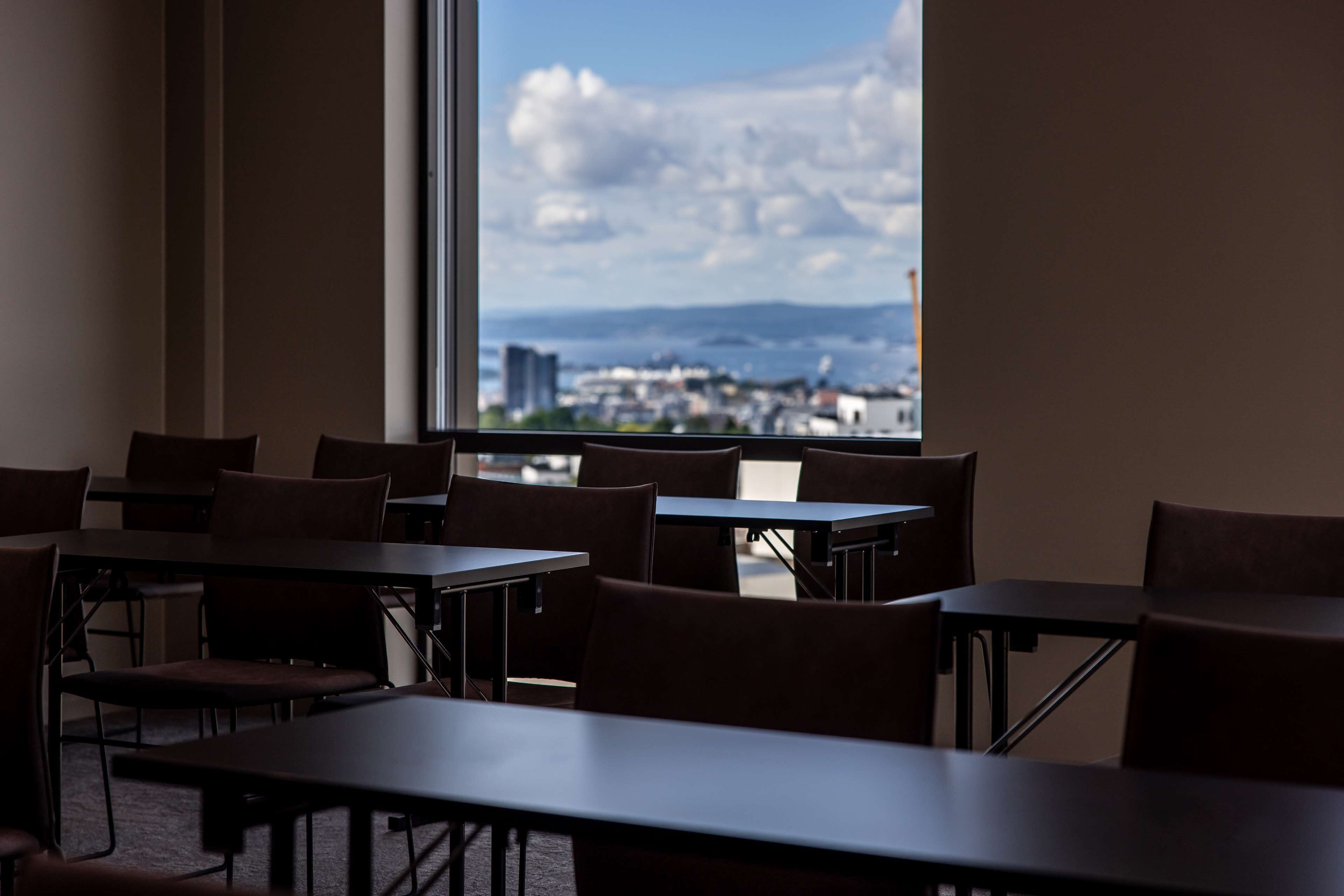 A dining area with tables and chairs, large windows with a city view.
