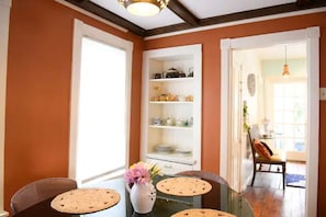 A dining area with a table, chairs, and a white cabinet with shelves. - Vintage Charmer Waterfall views! sleeps 5! (Ithaca)