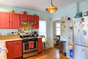 A kitchen with red cabinets, a stainless steel refrigerator, and a hanging light fixture. - Vintage Charmer Waterfall views! sleeps 5! (Ithaca)