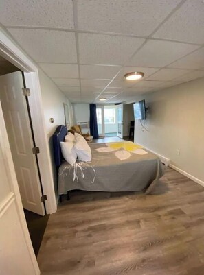 Quarto de hotel com uma cama, televisão e vista para o exterior.