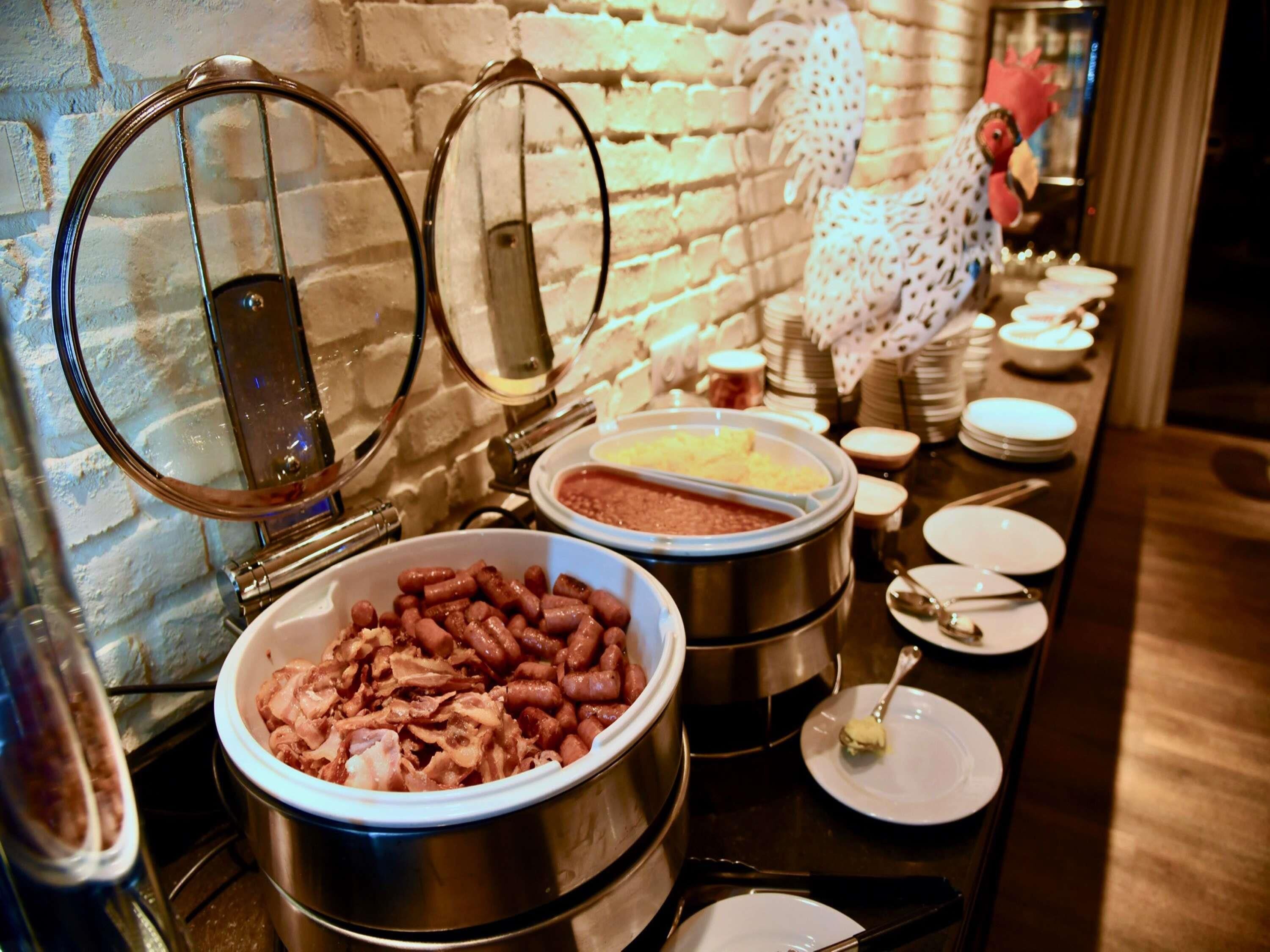 A buffet setup with various food items, including a large bowl of beans and a container of meat.
