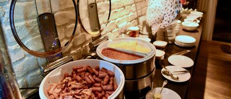 A buffet setup with various food items, including a large bowl of beans and a container of meat.