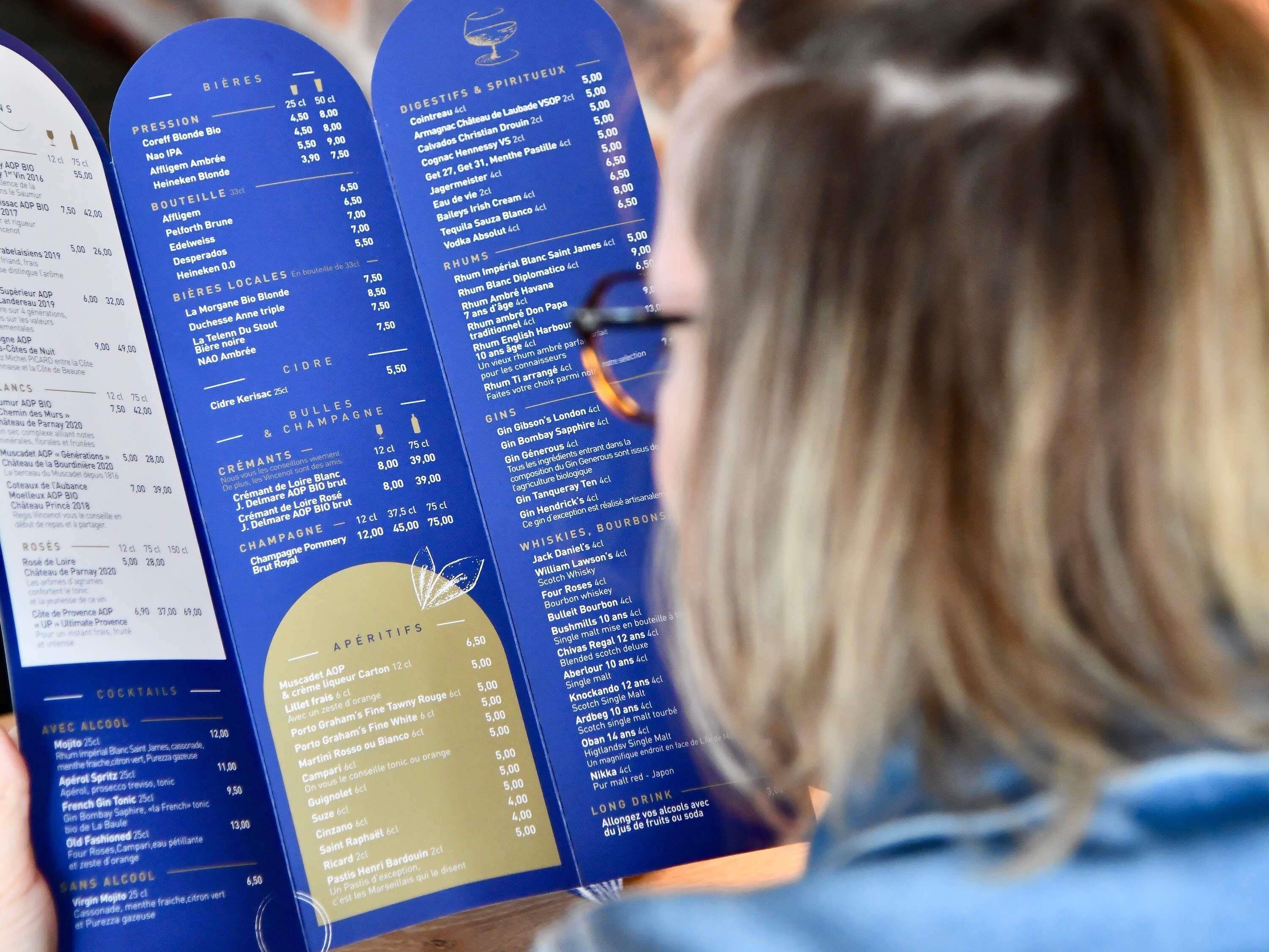 Una persona sosteniendo un menú con diferentes opciones de bebidas y sus precios.