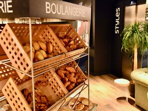 A bakery display with pastries and bread, a sign reading 'BOULANGERIE,' and a plant in the background. - ibis Styles Saint Nazaire Centre Gare (Saint-Nazaire)