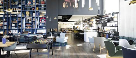 A modern library with bookshelves, a foosball table, and a bar area.