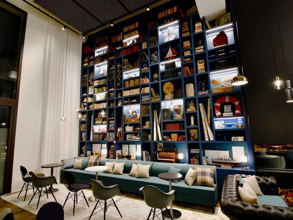 A room with a large bookshelf, a sofa, and a table with chairs. - ibis Styles Saint Nazaire Centre Gare (Saint-Nazaire)