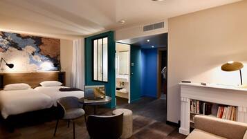 Habitación de hotel con cama, escritorio con ordenador portátil, silla, estantería, mapa en la pared y chimenea.