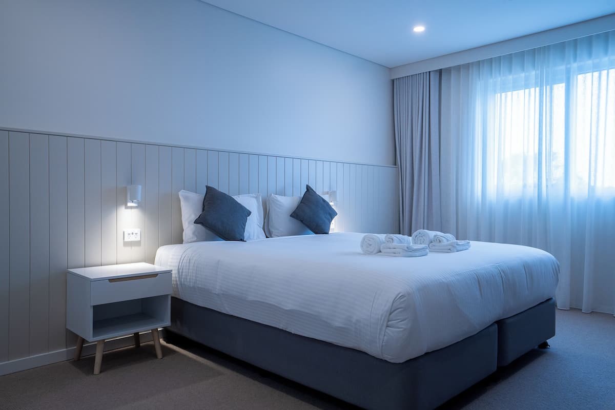 Ein modernes Hotelzimmer mit einem großen Bett, einem Nachttisch und einem Beistelltisch.