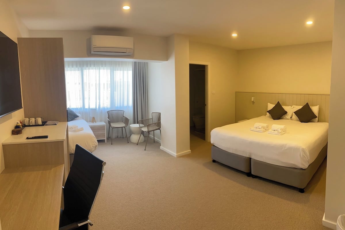 Ein Hotelzimmer mit Bett, Schreibtisch, Stuhl und einem kleinen Tisch.