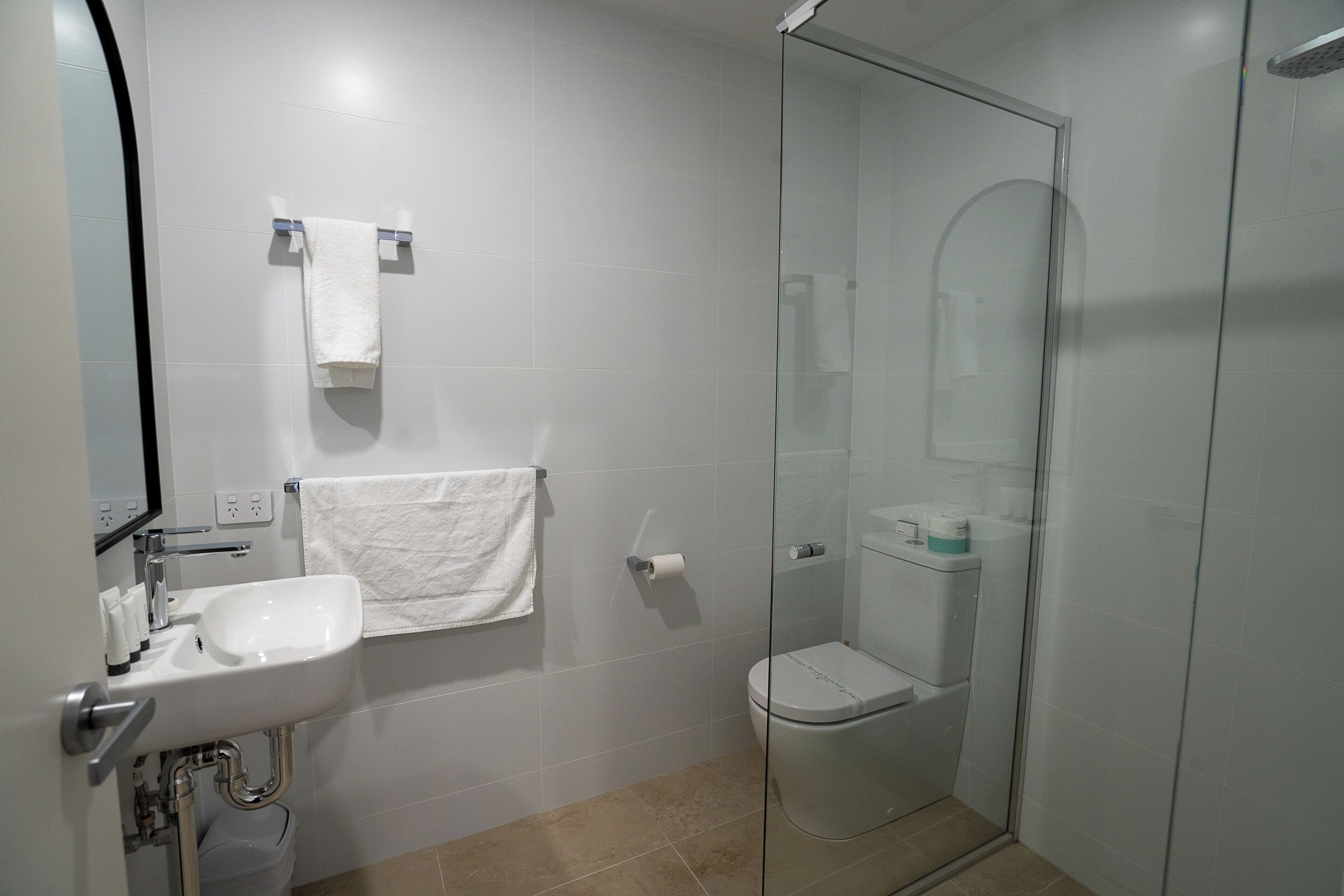 A modern bathroom with a glass shower enclosure, a white sink, and a toilet.