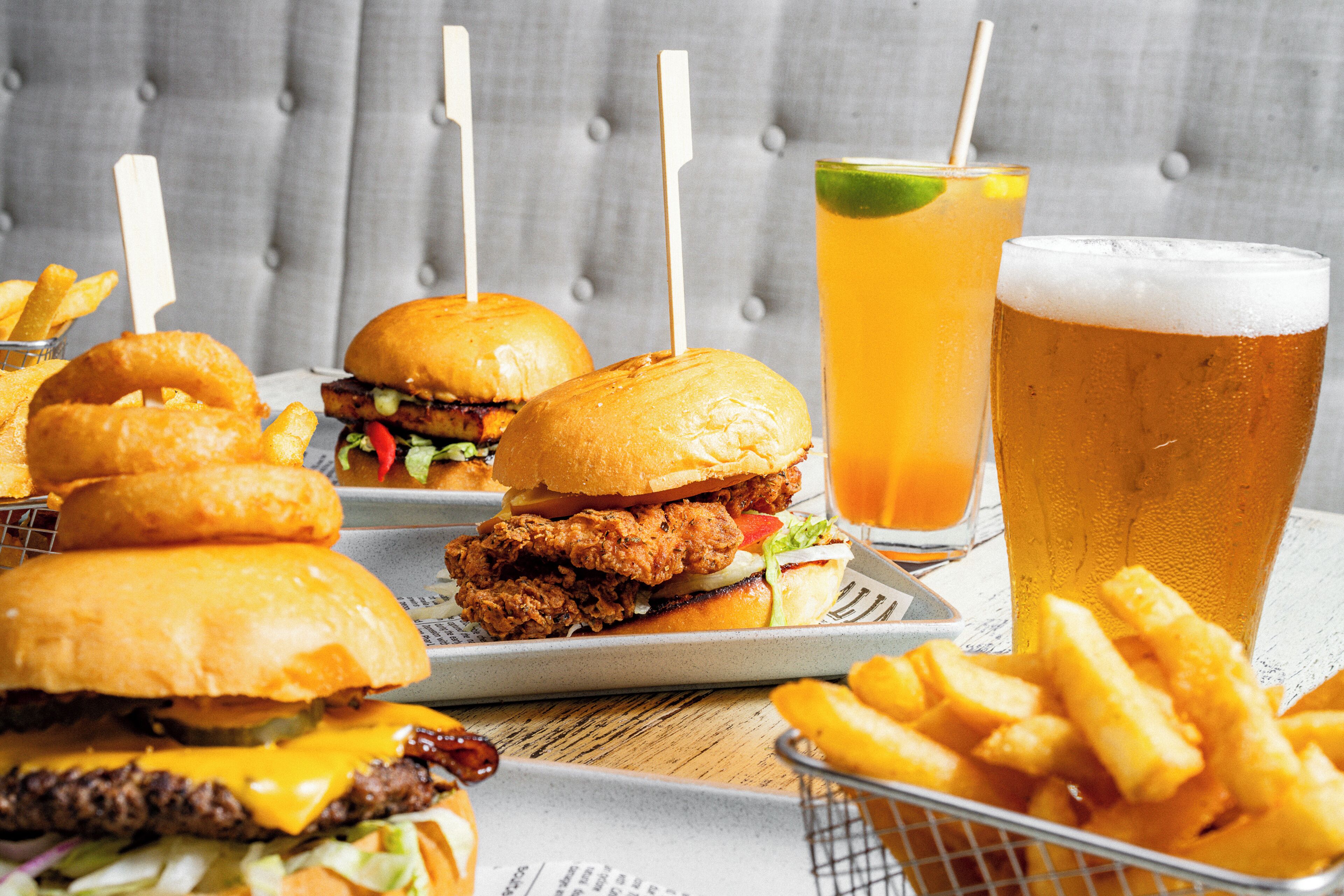 Una mesa con hamburguesas, papas fritas y una jarra de cerveza.