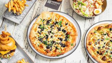 A table with a variety of food items including pizzas, fries, and a salad.