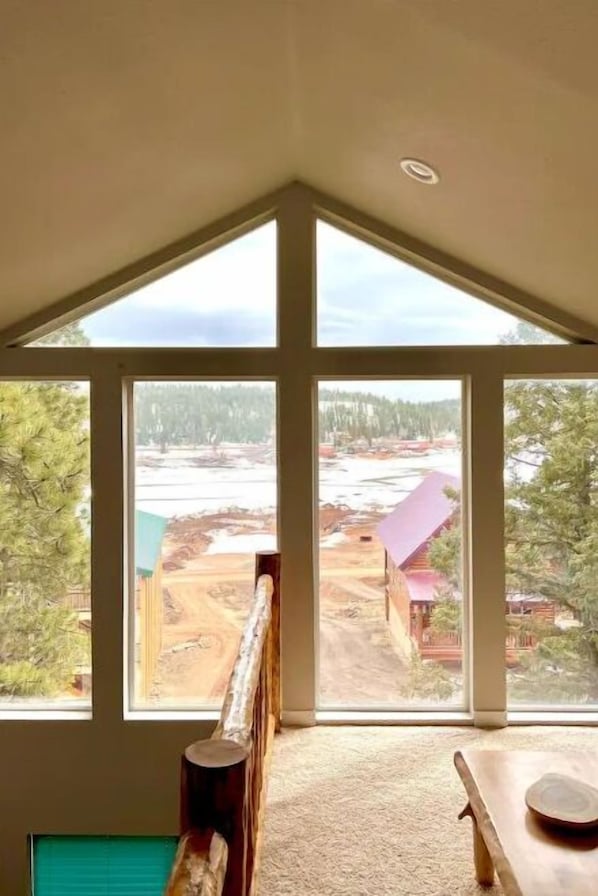 A room with a large window offering a view of a construction site and trees.