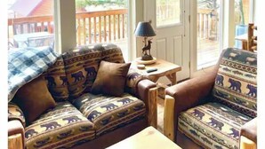 A cozy room with a sofa and armchair, a lamp, and a 'WELCOME' sign.