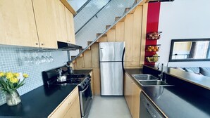 A modern kitchen with wooden cabinets, a stainless steel refrigerator, a gas stove, and a dishwasher.