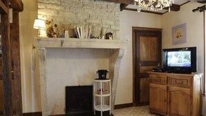 Ein gemütliches Wohnzimmer mit Kamin aus Stein, Holzschränken und einem Fernseher.