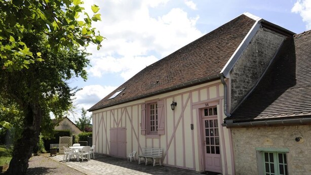 Ein traditionelles Gebäude mit einem geneigten Dach, einer kleinen Veranda mit einer Bank und einer Tür, die mit der Nummer 94 gekennzeichnet ist.