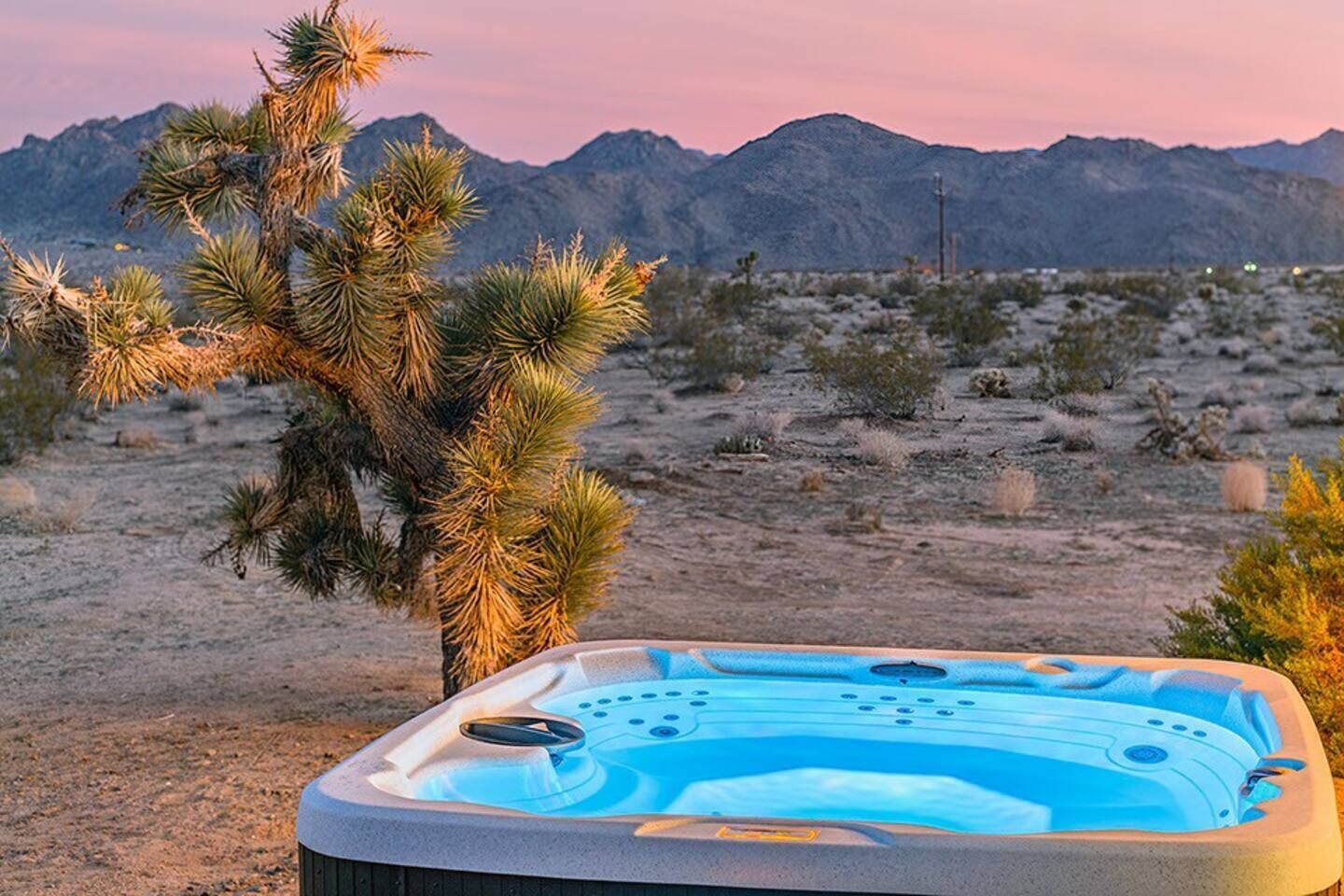 A hot tub in a desert landscape with mountains in the background.
