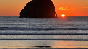 A rock formation silhouetted against a sunset at the beach. - Very quiet Pacific City home with amazing river views from the deck! (Cloverdale)