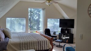 A bedroom with a bed, a desk, a chair, a TV, and a bookshelf. - Very quiet Pacific City home with amazing river views from the deck! (Cloverdale)
