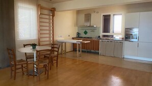 A spacious kitchen with wooden flooring, a dining area with a round table and chairs, and a built-in oven and microwave. - Under The Moon: House in the Countryside Family Apartment with Balcony and Garden (Castel Bolognese)