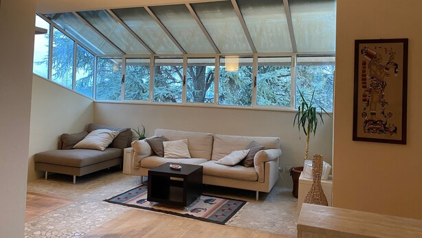 A spacious living room with a high ceiling, large windows, a sofa, a coffee table, and a decorative vase. - Under The Moon: House in the Countryside Family Apartment with Balcony and Garden (Castel Bolognese)
