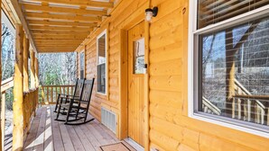 A wooden cabin with a porch, rocking chairs, and a window with a view of trees. - Linville Gorge 2 Bd 1 Bth Mountain Getaway! (Newland)