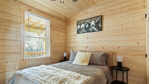 A wooden-paneled bedroom with a bed, two bedside tables, a window with blinds, and a wall-mounted picture. - Linville Gorge 2 Bd 1 Bth Mountain Getaway! (Newland)