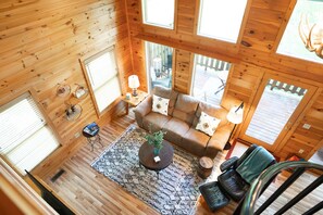 A wooden cabin interior with a sofa, coffee table, and a view of the outside deck. - New Listing -Couples Retreat (Sevierville)