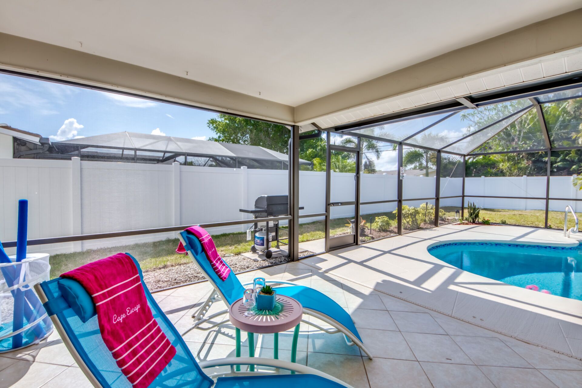 Un patio couvert avec une piscine, des chaises longues et un barbecue.