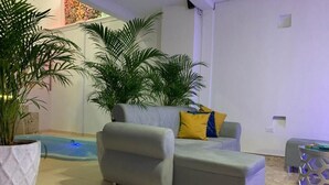 A living area with a grey sofa, a small pool, and potted plants. - Casa Gran Fuente (Cartagena)